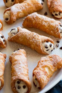 several pastries on a white plate with chocolate chips and powdered sugar around them