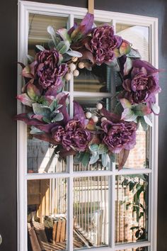 a wreath with purple flowers hanging on a window