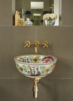 a bathroom sink sitting under a mirror in front of a wall mounted faucet