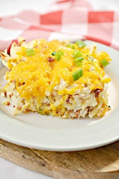 a white plate topped with rice covered in cheese and green onions on top of a checkered table cloth