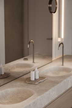 two sinks with soap dispensers on them in a public bathroom area that appears to be empty