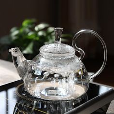 a glass tea pot sitting on top of a metal burner with water in it