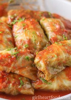 stuffed cabbage rolls with marinara sauce and parsley on top in a white bowl