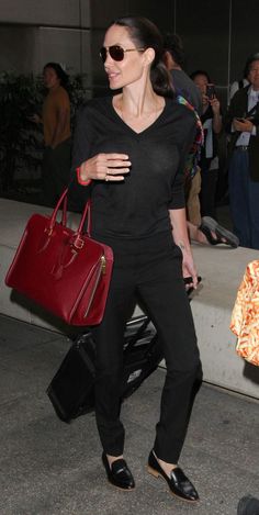 a woman carrying a red handbag while walking through an airport