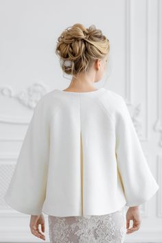 the back of a woman's white jacket, with lace on the bottom and sleeves