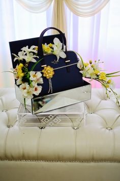 the purse is sitting on top of the ottoman with flowers in it and another bag next to it