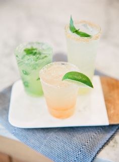 three different types of drinks sitting on top of a white square plate next to each other