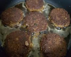 some meat patties are cooking in a pan on the stove top and it looks like they have been cooked