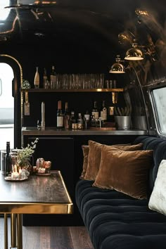 a living area with couches, tables and shelves filled with bottles on the wall