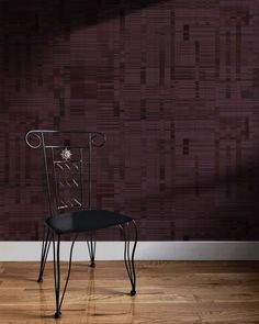 a black chair sitting on top of a hard wood floor next to a purple wall