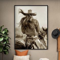 a black and white photo of a woman with a cowboy hat sitting on a horse