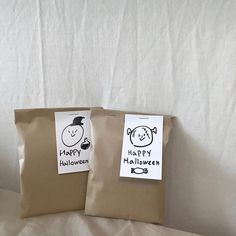 two brown bags with happy halloween stickers on them sitting on a white sheeted surface