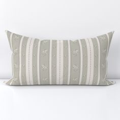 a gray and white striped pillow sitting on top of a table next to a wall