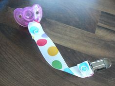 a pacifier sitting on top of a wooden table next to a bottle opener with polka dot design