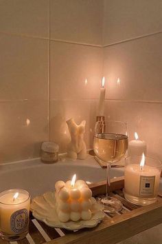 candles sit on a tray in front of a bathtub