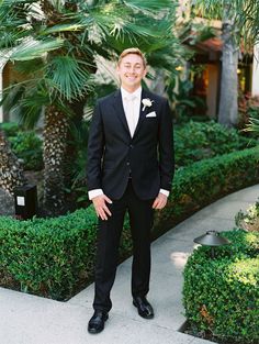 a young man in a tuxedo poses for a photo at his wedding day