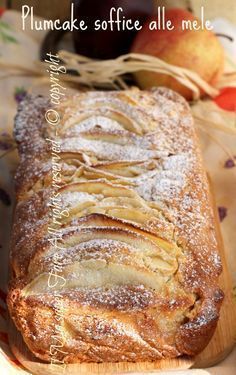 a loaf of bread sitting on top of a wooden cutting board next to an apple