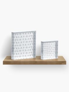 two small boxes on a wooden shelf against a white background with polka dotty designs