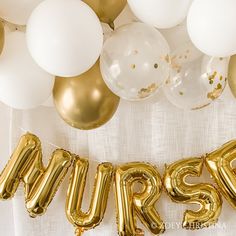 the word mrs spelled out in gold and white balloons on top of a table cloth