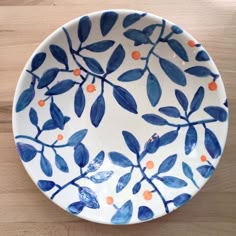 a blue and white plate with orange dots on the rim sits on a wooden surface