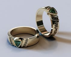 two gold wedding rings with green and white diamonds on them, sitting next to each other