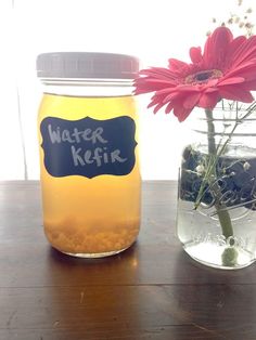 a mason jar with water kefir next to a flower in a glass vase