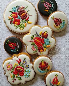 several decorated cookies sitting on top of a white cloth covered table next to each other