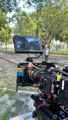 a camera attached to the back of a vehicle in front of a tree and road