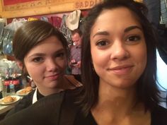 two women standing next to each other in front of a table with food on it