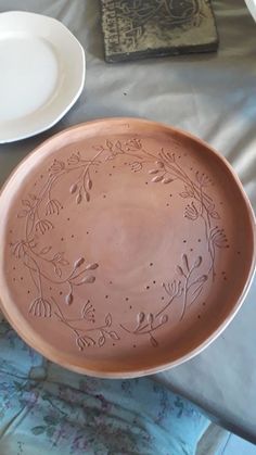 a bowl sitting on top of a bed next to two plates and an empty plate