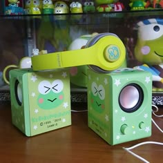 two green toy speakers sitting on top of a wooden table in front of other toys