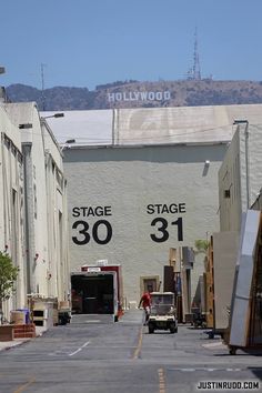 an alley way with cars parked on both sides and large buildings in the back ground