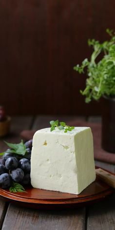 a piece of cheese sitting on top of a plate next to blueberries and greens