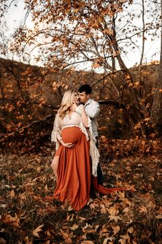 a pregnant woman in an orange dress standing next to a man