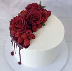 a white cake topped with raspberries and drizzled chocolate