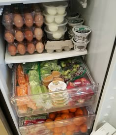 an open refrigerator filled with lots of different types of vegetables and eggs in plastic containers