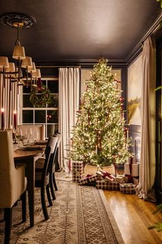 a christmas tree in the middle of a room next to a dining table and chairs