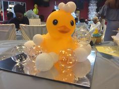 a yellow rubber duck sitting on top of a table next to wine glasses and bubbles