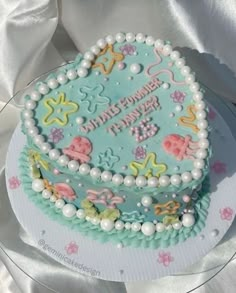 a decorated birthday cake on a plate with pearls