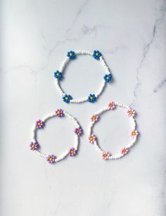 These cheerful floral bracelets are perfect for spring and summer! They're made with an elastic cord that allows them to easily slip on and off. This style is made from white beads with a multi flower detail. If you need a different size or would like to customize the colors, just message me! Matching rings available! https://www.etsy.com/listing/998861261/beaded-flower-ring-flower-seed-bead-ring?ref=shop_home_recs_4&crt=1 Flower Shaped Beaded Bracelets For Beach In Spring, Spring Beach Beaded Bracelets With Flower Shape, Floral Beaded Bracelets For Beach And Spring, Matching Seed Bead Bracelets, Spring Flower Beaded Bracelets For Beach, Spring Bracelets With Adjustable Flower Decoration, Adjustable Bracelet With Flower Decoration For Spring, White Beaded Bracelets With Flower Charm For Spring, Adjustable Spring Bracelet With Flower Decoration