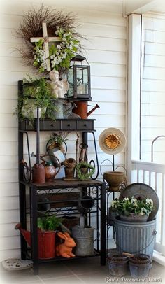 a shelf filled with potted plants on top of a porch