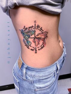 a woman's stomach with a compass tattoo on it