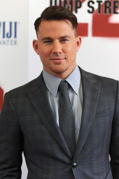 a man in a suit and tie posing for the camera at a red carpet event