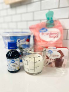 ingredients for chocolate cake sitting on top of a white counter next to a measuring cup