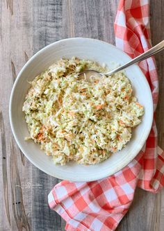 a white bowl filled with coleslaw on top of a red and white checkered napkin