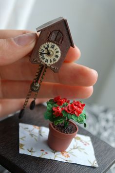 a miniature house with a clock on the front and a potted plant in it