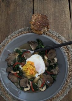 a bowl filled with soup next to a piece of bread on top of a wooden table