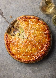 a pie with a spoon in it sitting on a table next to some wine glasses