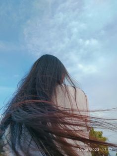 the back of a woman's head with long hair flying in the air above her