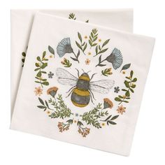 two white napkins with embroidered bees and flowers on them, one has a bee in the center